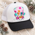 Colorful snowman face DTF transfer with polka-dot striped hat, carrot nose, pink cheeks, and winking eyes framed by a fringed border Shown on a white front panel, black pre-curved bill, white mesh back trucker hat.