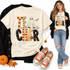 TEACHER Halloween DTF transfer in patchwork block letters with checkerboard, stripes, polka dots and stars, featuring a ghost, jack-o'-lantern, and bats Shown on a Ivory t-shirt.
