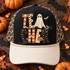 TEACHER Halloween DTF transfer in patchwork block letters with checkerboard, stripes, polka dots and stars, featuring a ghost, jack-o'-lantern, and bats Shown on a black front panel with ivory bill and rope, leopard-print mesh back trucker hat.