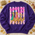 Tonight We Ride DTF transfer featuring the Three Wise Men riding camels in colorful robes, on a pink and white polka-dot striped background with scattered stars Shown on a Purple crewneck sweatshirt.