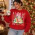 Holly Jolly Christmas DTF transfer with fluffy white tree, pink gingham bow, gold star, ornaments, and bubble lettering on a red striped polka dot background Shown on a Cherry Red crewneck sweatshirt.