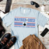 Top Gun You've Lost That Loving Feeling Screen Print Heat Transfer T-shirt, with Maverick Goose graphic and patriotic design, laid on a rustic wooden surface surrounded by shoes, sunglasses, a smartphone, and accessories.