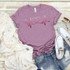 Healthcare Lifeline Screen Print Heat Transfer, pink T-shirt with heart and heartbeat line design, casual outfit with denim shorts, white sneakers, and sunglasses on wooden background.