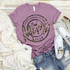 Bad Moms Club Screen Print Heat Transfer, purple T-shirt with leopard print design and text, paired with denim shorts, white sneakers, and sunglasses on wooden background.