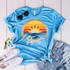 Sunrise Sunburn Sunset Screen Print Heat Transfer, a graphic t-shirt with a sunset and sunflower design with the words "Repeat" on a light blue background.