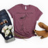 Whisper Words Of Wisdom Let It Be Daisy Screen Print Heat Transfer T-shirt with floral and bird design, paired with ripped jeans, sunglasses, flowers, and brown cutout ankle boots.