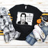On Wednesday We Wear Black Screen Print Transfer, a black T-shirt with a graphic of a girl drinking a poison bottle and the text 'On Wednesday We Wear Black' on a flat lay background with jeans, sneakers, and Halloween-themed pumpkins.