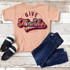 Give Thanks Tie Dye Youth Screen Print Heat Transfer, colorful tie dye design with the message 'Give Thanks' on a peach youth T-shirt, paired with dark jeans and sneakers.
