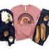 Autumn Vibes Rainbow Screen Print Heat Transfer, a pink T-shirt with a colorful rainbow and autumn design, laid out with denim jeans and brown shoes.
