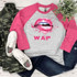 Wet Lips Screen FINAL STOCK Print Heat Transfer, a graphic design featuring pink lips with a shiny, glossy finish and bold letters WAP underneath, on a casual shirt with pink sleeves and gray body.