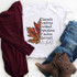 It's Fall Sublimation Transfer, a white t-shirt featuring fall-themed text and an autumn leaf graphic, paired with a maroon cardigan, distressed jeans, and brown lace-up boots for fall fashion.