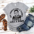 Not Fragile Like a Flower RBG Screen Print Transfer, gray t-shirt with a graphic of Ruth Bader Ginsburg and the quote 'Not Fragile Like a Flower, Fragile Like a Bomb' displayed on a white wooden background.