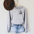 Not Fragile Like a Flower RBG POCKET/Mask Screen Print Transfer, front view of a gray hoodie with black text and graphic design on the chest, paired with denim shorts and a brown hat hanging on a hanger.