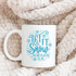 Let It Snow Somewhere Else Sublimation Transfer, white mug with blue winter-themed text and snowflake design on a soft, plush blanket.