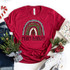 Merry And Bright Rainbow Screen Print Transfer, red Christmas-themed t-shirt with rainbow and tree design for festive holiday wear.