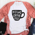 Resting Coffee Face Sublimation Transfer, white t-shirt with black coffee mug graphic and text, laid on pink lace cardigan and denim shorts on white wooden background.