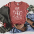 He Restores My Soul Screen Print Transfer, printed on a red t-shirt with white writing, surrounded by jeans, brown boots, a gray sweater, and greenery on a cozy blanket background.