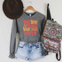 Take Time To Make Your Soul Happy Screen Print Heat Transfer, Grey sweatshirt with motivational quote in orange and red text, paired with denim shorts, brown hat on hook, and a patterned backpack hanging on the wall.