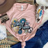 Flower Power Screen Print Heat Transfer on a pink t-shirt with floral and peace sign design, surrounded by bohemian accessories and a decorative skull with colorful feathers.