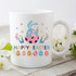Happy Easter Sublimation Transfer, a white ceramic mug with colorful Easter-themed design featuring a bunny emerging from an Easter egg, surrounded by flowers and decorated eggs.