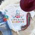 Happy Easter Sublimation Transfer, Easter-themed design on a white T-shirt with bunny and decorated eggs, surrounded by colorful jewelry, hat, and denim jeans.