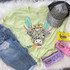 Shaggy Cow Easter Screen Print Heat Transfer, graphic of a cheerful cow with shaggy hair, wearing a colorful bow and bunny ears on a pastel yellow T-shirt.