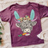 Shaggy Cow Easter YOUTH Screen Print Heat Transfer, colorful children's T-shirt featuring a shaggy cow with bunny ears, a bow, and a carrot in its mouth.
