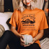 It's Just A Bunch Of Hocus Pocus Screen Print Transfer, an orange t-shirt featuring a Halloween-themed design with spooky house, bats, and text celebrating Salem, Massachusetts witch history.