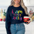I Am Freaking Jolly Screen Print, woman wearing a black sweatshirt with colorful holiday-themed text and decorations.