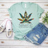 Namastay Home and Get High Humor Sublimation Transfer T-shirt, a mint green T-shirt featuring a colorful, intricate illustration of a person in a yoga pose with a large marijuana leaf and the humorous text 'Namastay Home and Get High' printed on it.