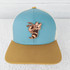 TAN Hornet Mascot Leather Hat Patch, embroidered patch of a cartoon hornet character on a two-tone hat with a light blue crown and a tan brim.
