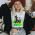 Skellie Mal DTF Transfer, a woman wearing a Halloween themed T-shirt featuring a cartoon witch with a skull face and bones, surrounded by green flames.