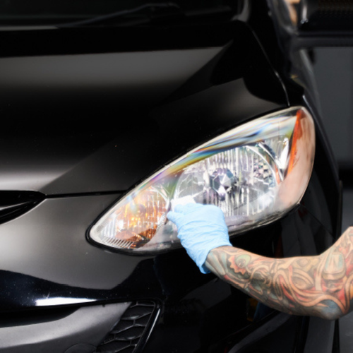 Driver applying Wipe New Headlight Restore Kit to oxidized lens for improved clarity