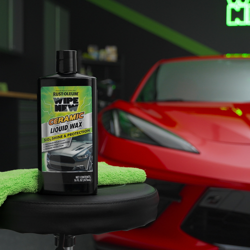 Bottle of Wipe New Ceramic Liquid Wax on stool in front of red sports car in garage