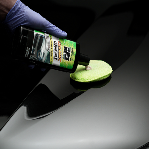 Hand in glove applying Rust-Oleum Wipe New Ceramic Liquid Wax to black car hood with microfiber applicator.