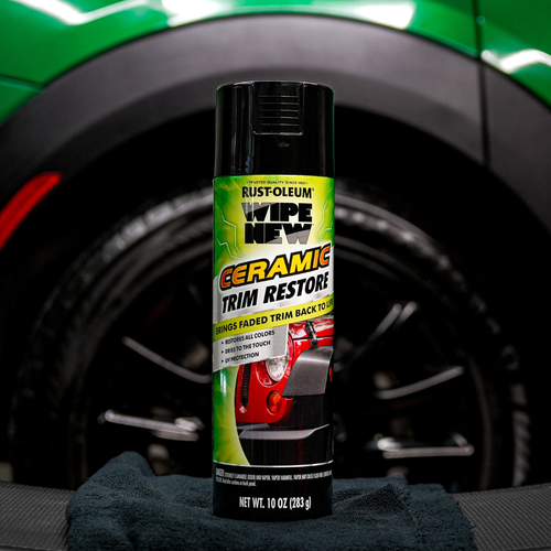 Wipe New Ceramic Trim Restore can displayed in front of black wheel and green fender, ideal for restoring faded exterior car trim