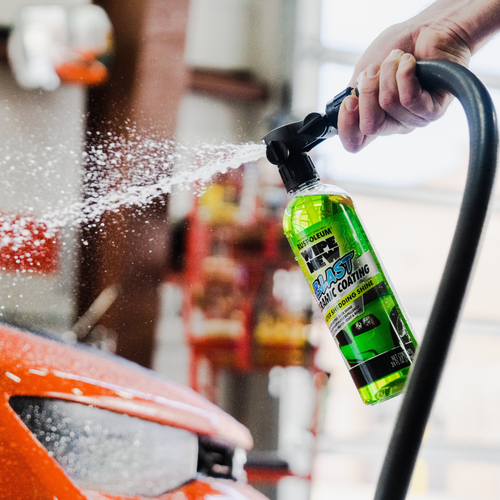 Close-up of Wipe New Blast Ceramic Coating bottle connected to sprayer in auto detailing garage