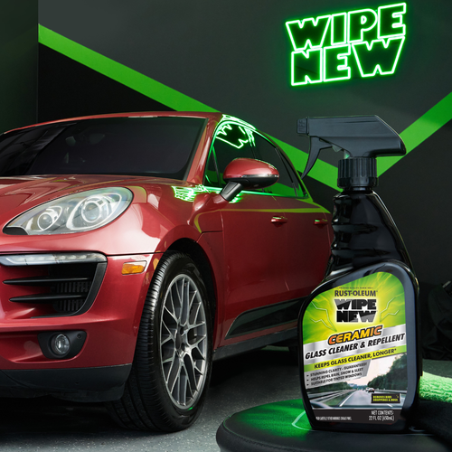 Stylized product shot of Wipe New Ceramic Glass Cleaner & Repellent in front of a red SUV in a showroom-style setting