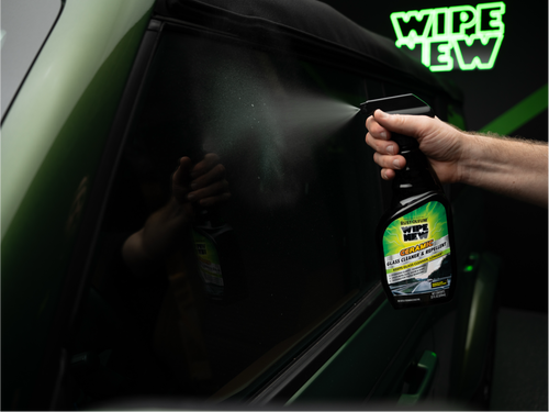 A person sprays Rust-Oleum Wipe New Ceramic glass cleaner on a car window.