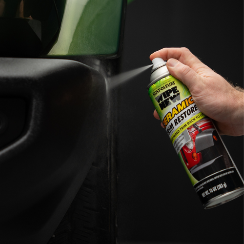 A person using Rust-Oleum Wipe New Ceramic Trim Restore spray on a vehicle's faded edge.