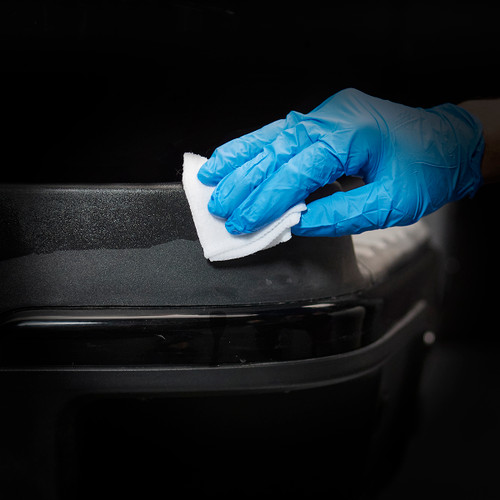 A person with blue gloves cleaning a trim surface with a cloth.