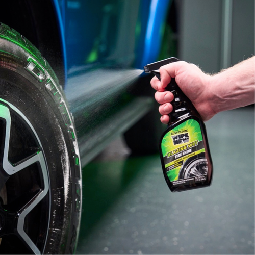Rust‑Oleum Wipe New Blazing Wet Tire Shine trigger spray being applied to a vehicle tire, with mist spraying onto the tire sidewall