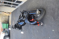 Passenger peg crash bar frame slider on Harley M8 Softail (2018-2025) with bike laid over showing protection from tip-over, replaceable Delrin puck, gloss black finish
