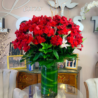 Blooming Poem is a large luxury arrangement dominated by signature red roses mixed with white lilies with and lush green foliage, arranged in  tall glass cylinder vase  by Lexis Florist Houston