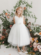 This Communion dress has a V Neckline and a glitter tulle skirt. The dress also comes with a removable rhinestone brooch. The back has a center zipper and a sash tie back. 
3 dress limit per order