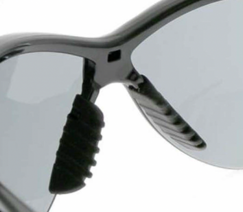 Close-up of safety glasses with gray lens and black rubber nose piece detail