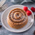 A mini caramel cake on a plate with raspberries.