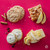 Assorted baked treats including a frosted cookie, apple dessert bar, lemon bar, and oatmeal cookie on a pink background.