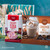 Tastefully Simple Cherry Soda Dip Mix and Cinnamon Roll Cookie Mix displayed in front of a wrapped gift box.
