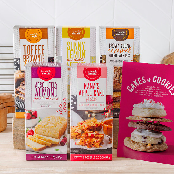 Assortment of Tastefully Simple baking mixes including Absolutely Almond Pound Cake Mix™, Nana's Apple Cake Mix®, Toffee Brownie Mix, Sunny Lemon™ Pound Cake Mix, Brown Sugar Caramel Pound Cake Mix, and a Cakes or Cookies recipe sheet. 